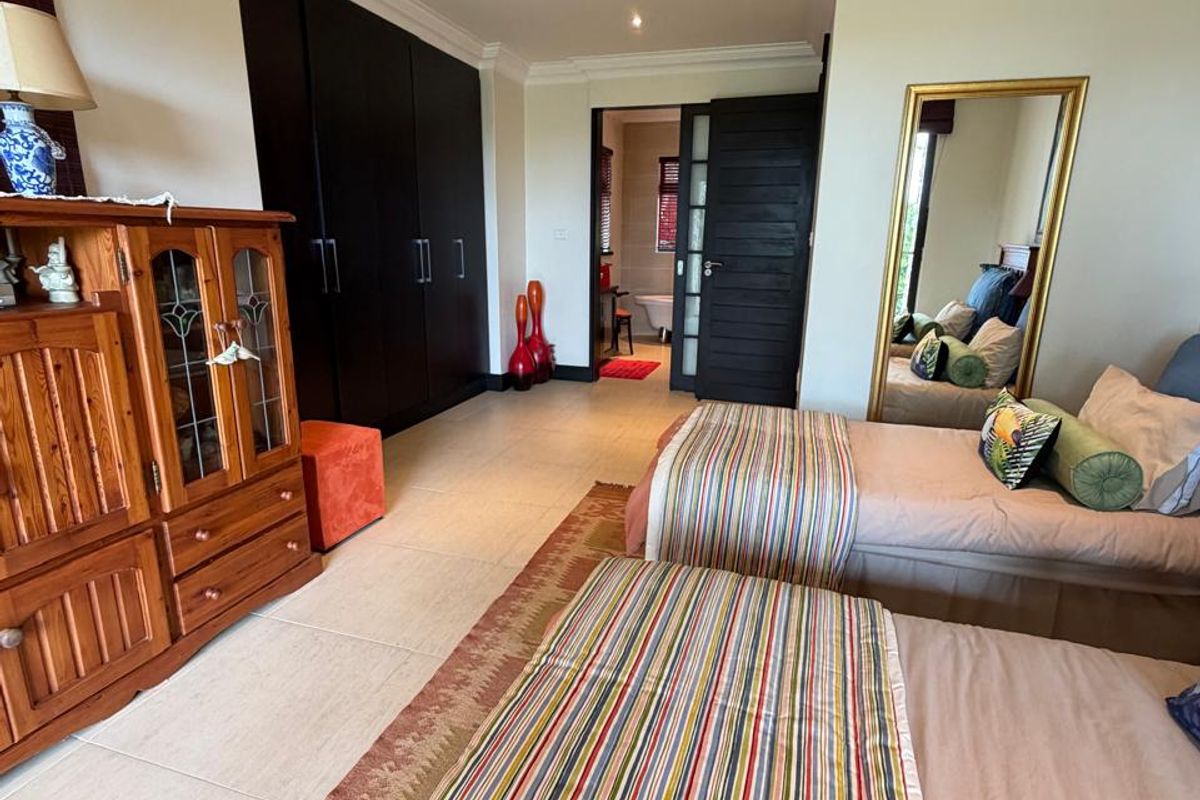 Spacious bedroom featuring built-in dark wood cabinetry, tiled flooring, recessed downlighting, and an en-suite bathroom access.