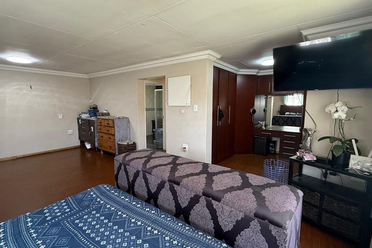 Spacious bedroom featuring built-in wooden cabinetry, laminate flooring, and an en-suite bathroom access point.