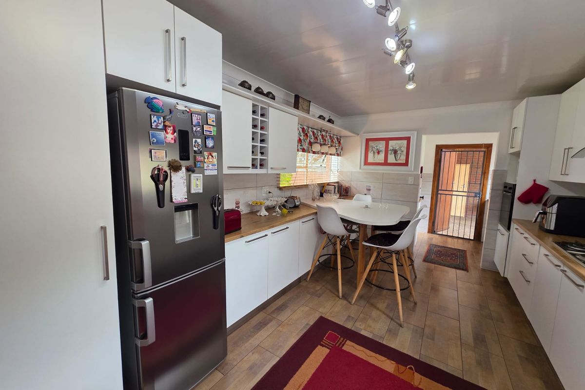 A functional kitchen featuring white cabinetry, wood-look countertops, tiled backsplash, and integrated lighting, providing a practical space for cooking and casual dining.