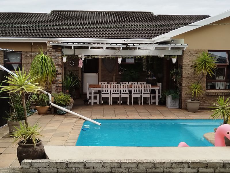 Rear exterior view featuring a swimming pool, paved patio area, and brick facade with a tiled roof.