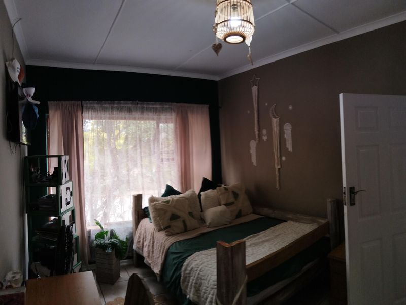 A bedroom featuring tiled flooring, a standard panel door, and a window with curtains, providing a functional living space.