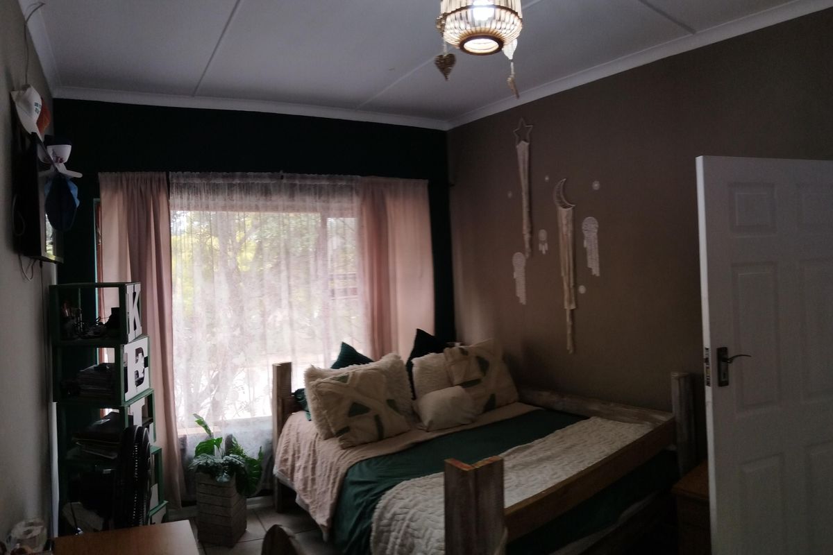 A bedroom featuring tiled flooring, a standard panel door, and a window with curtains, providing a functional living space.