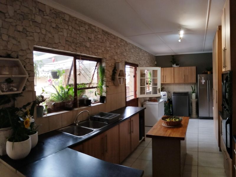 Spacious kitchen featuring a stone veneer feature wall, ample laminate cabinetry, a central island, and direct access to the outdoor area.