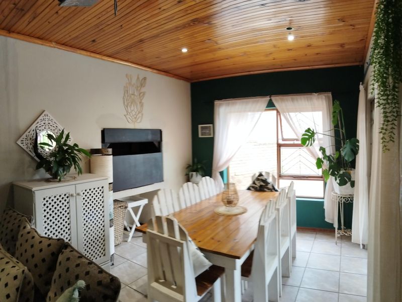 A dining room featuring a warm timber tongue and groove ceiling, tiled flooring, and natural light through a window with security bars.