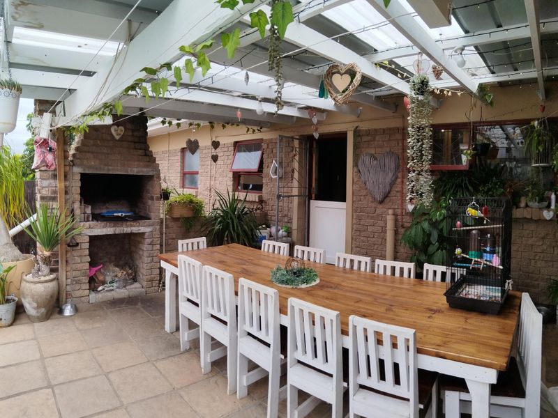 Covered outdoor patio area featuring a built-in brick braai, pergola roof structure, and tiled flooring, ideal for alfresco dining and entertaining.