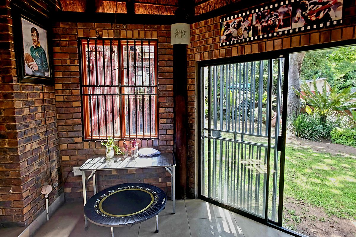 A rustic living area featuring exposed brick walls, a thatched roof, and large sliding glass doors providing direct access to the garden.