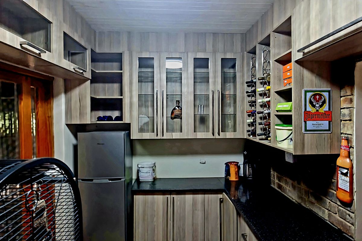 A compact kitchen area featuring wood-grain cabinetry, dark countertops, and a brick feature wall, providing functional storage and preparation space.