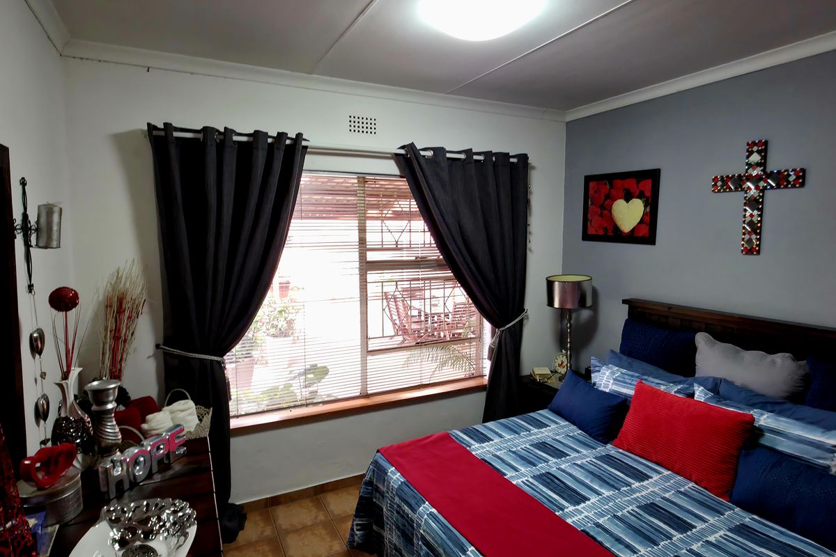 A bedroom featuring tiled flooring, a window with fitted blinds, and a ceiling light fixture.
