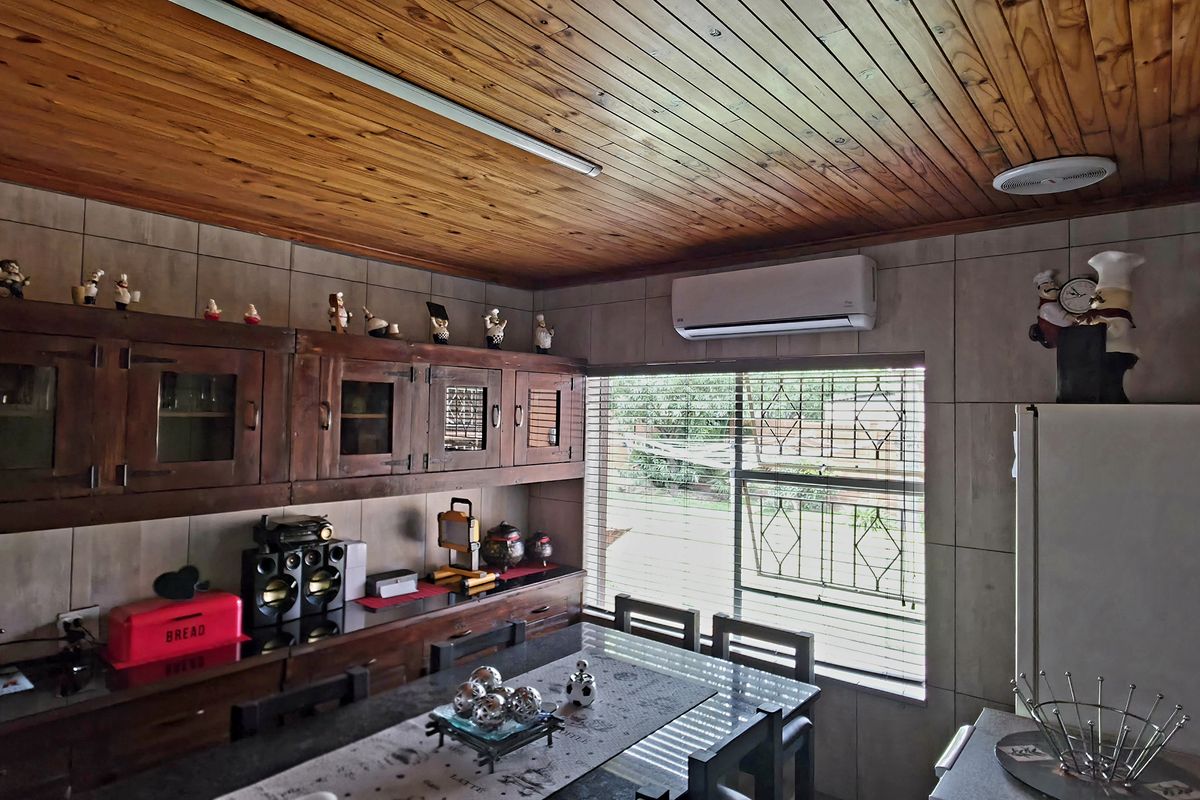 A kitchen featuring wooden ceiling paneling, tiled walls, and built-in wooden cabinetry, equipped with a wall-mounted air conditioning unit.