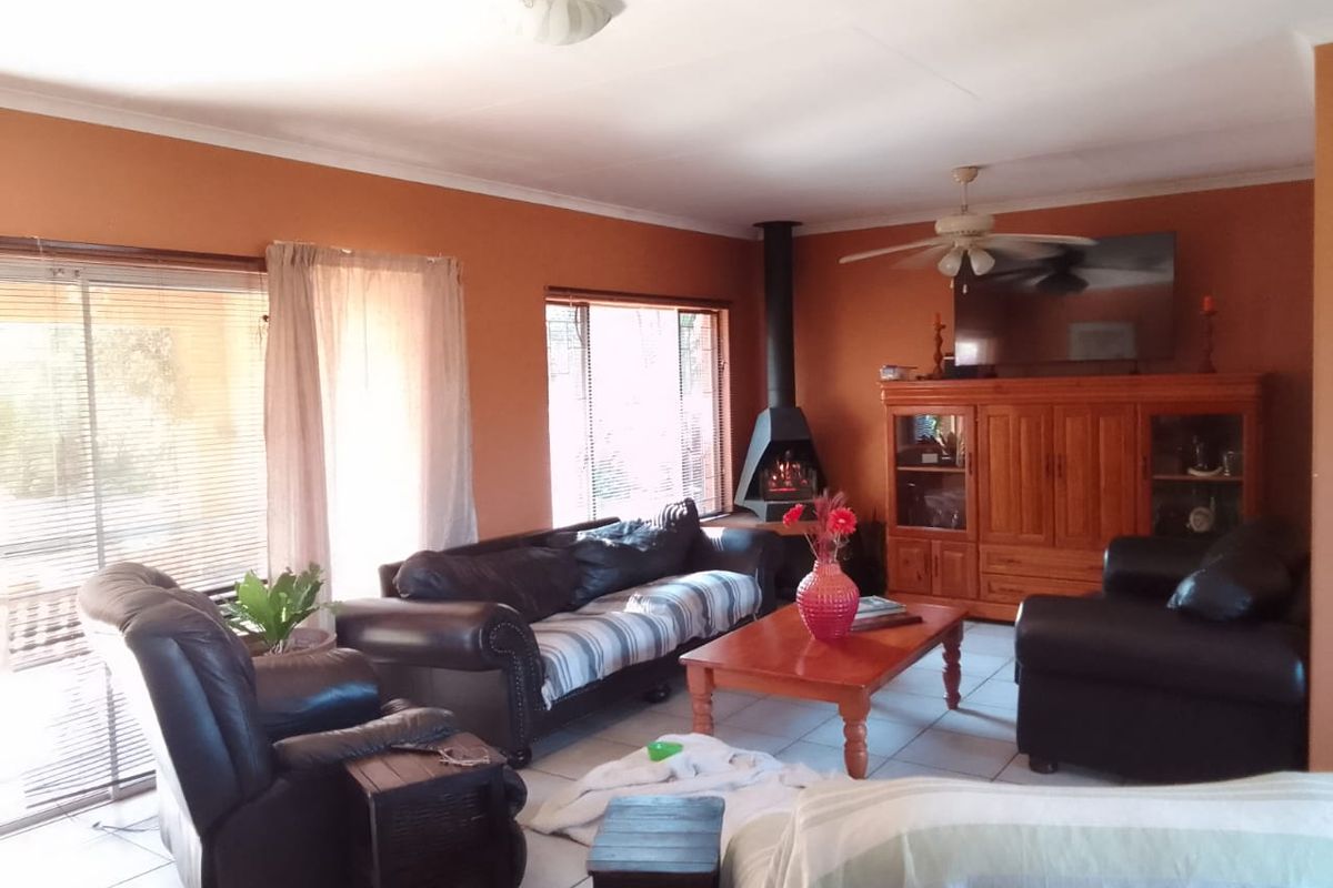Spacious living room featuring a freestanding fireplace, ceiling fan, and tiled flooring with direct access to the outdoor area through sliding glass doors.