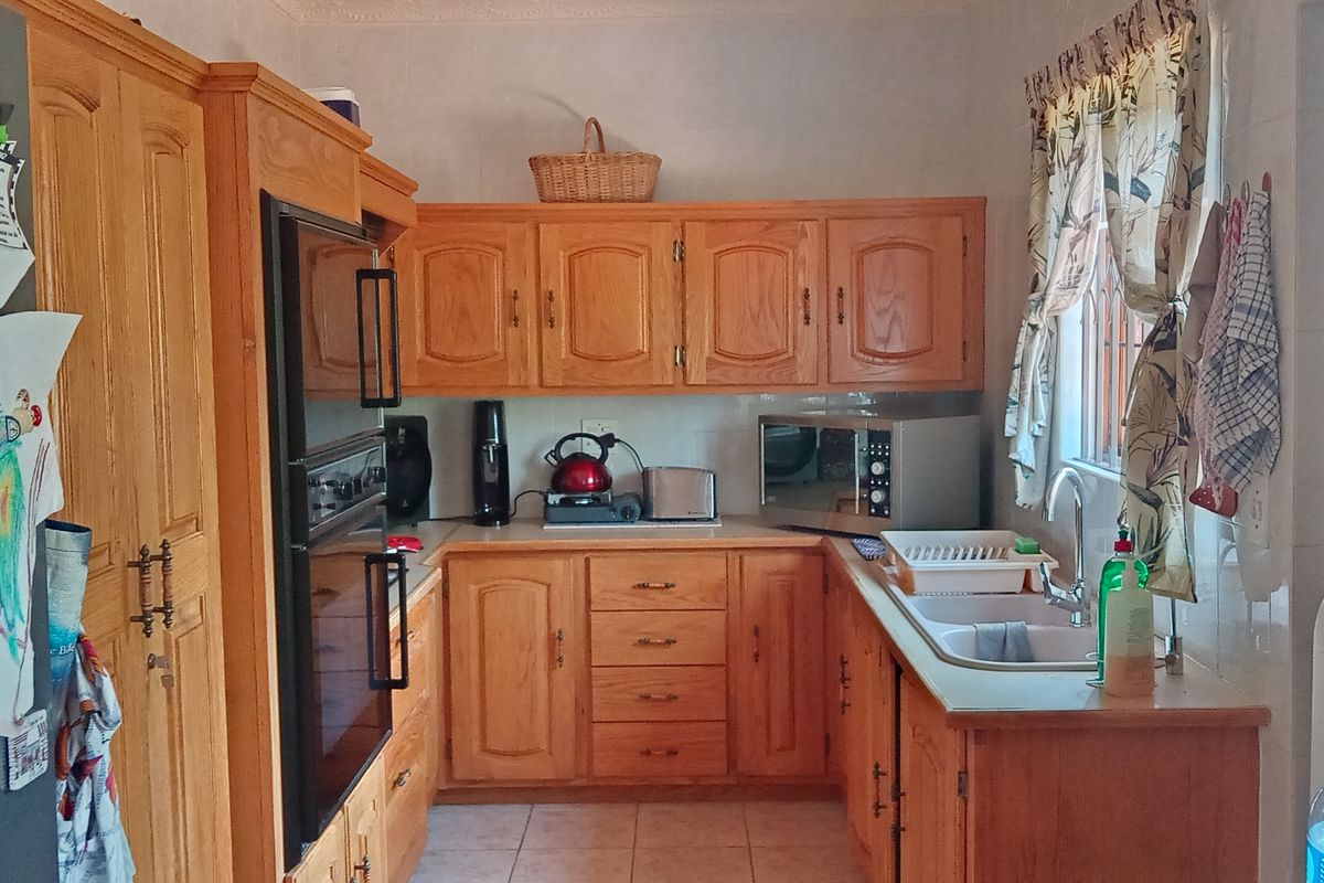 A functional kitchen featuring traditional timber cabinetry, a built-in oven, and a double-basin sink with tiled splashbacks.
