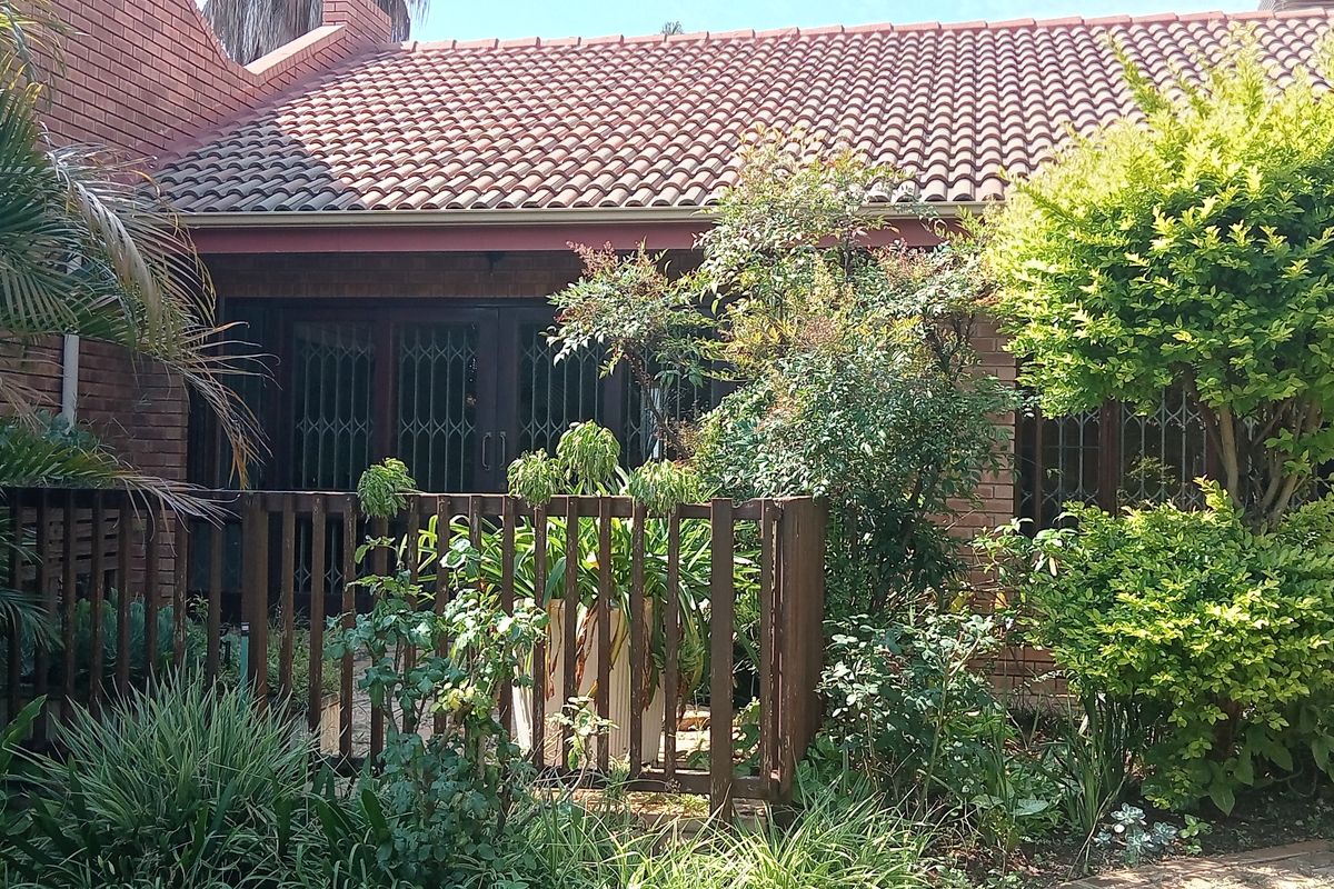 A view of the townhouse rear exterior featuring a brick facade, terracotta tiled roof, and a private garden area with timber fencing.