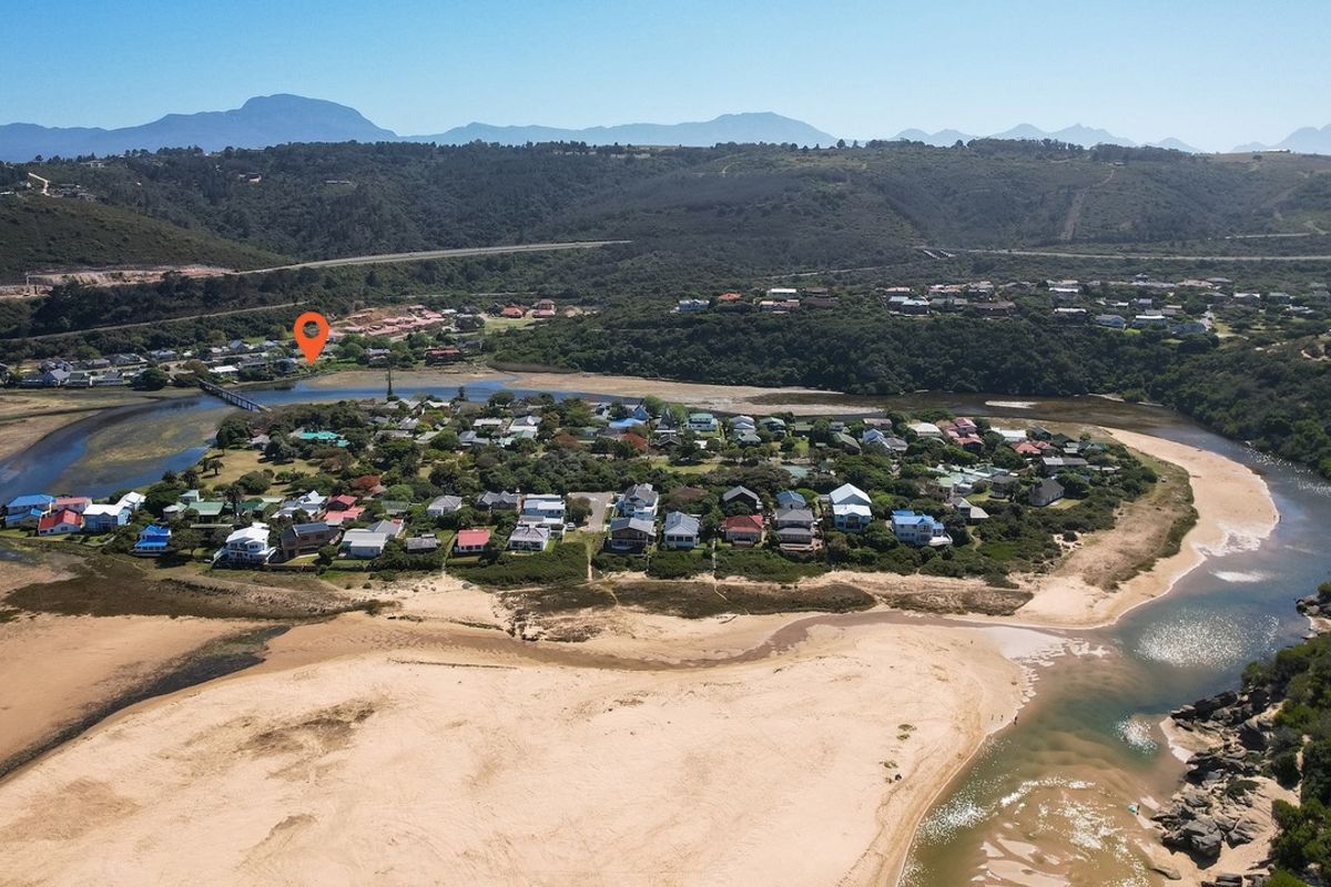 Aerial view of a coastal residential estate situated on a river estuary, featuring proximity to sandy beaches and natural landscape surroundings.