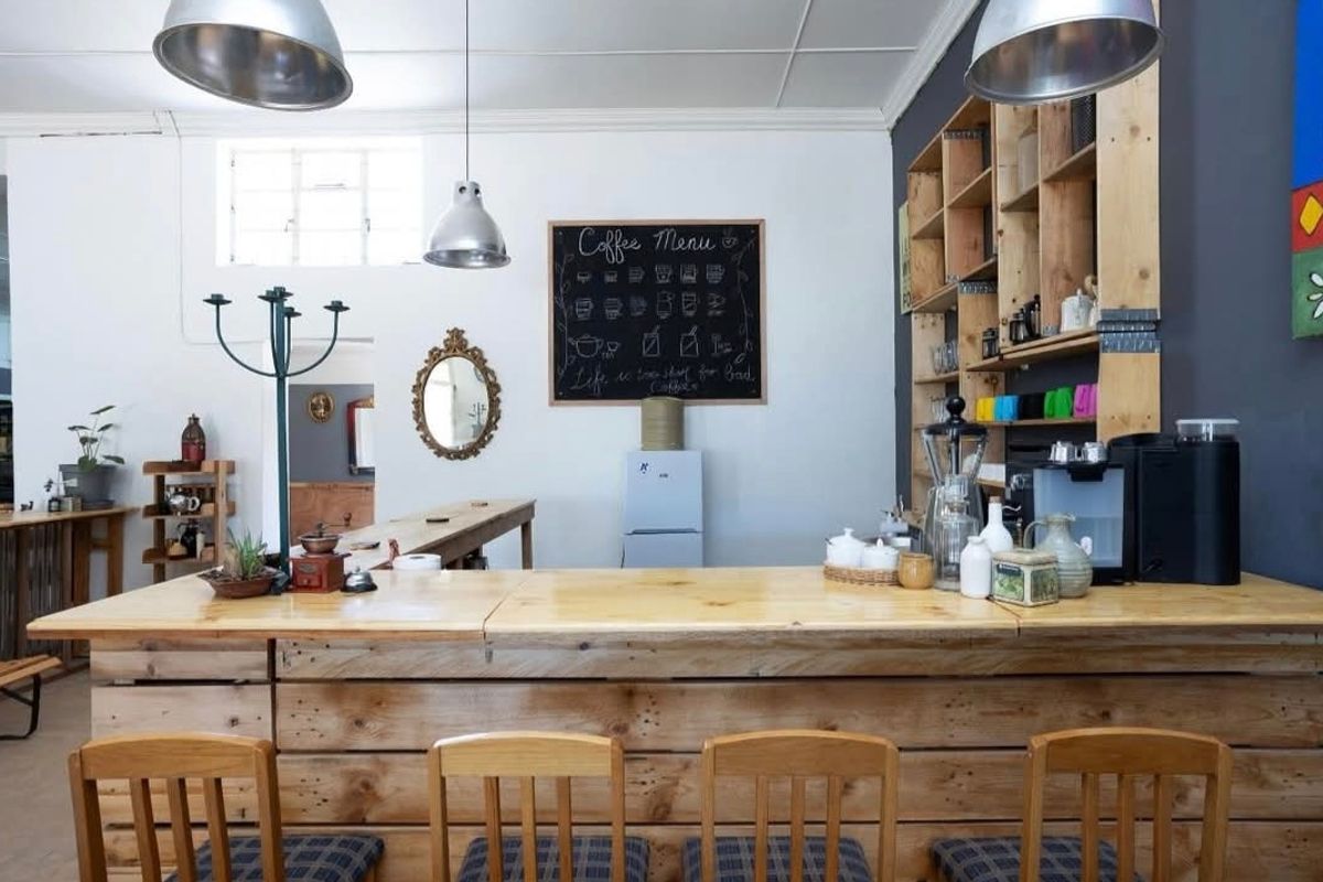 A rustic-style kitchen area featuring a custom timber breakfast bar, open shelving, and industrial-style pendant lighting.