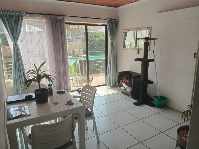 A living area featuring tiled flooring, a timber ceiling, and sliding glass doors providing direct access to the outdoor pool area.