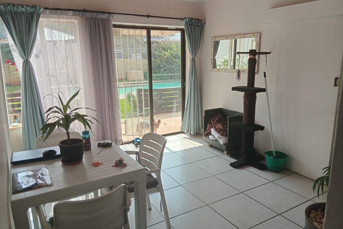 A living area featuring tiled flooring, a timber ceiling, and sliding glass doors providing direct access to the outdoor pool area.