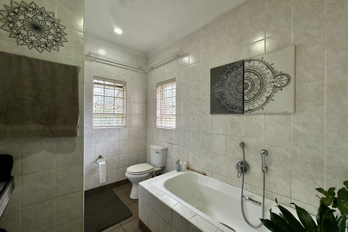 A functional bathroom featuring a built-in bathtub, toilet, and neutral wall tiling, offering a clean and practical space.