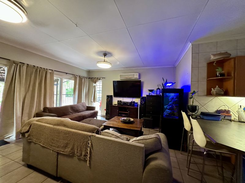 Open-plan living area featuring tiled flooring, a split-system air conditioner, and direct access to the outdoor space through sliding glass doors.