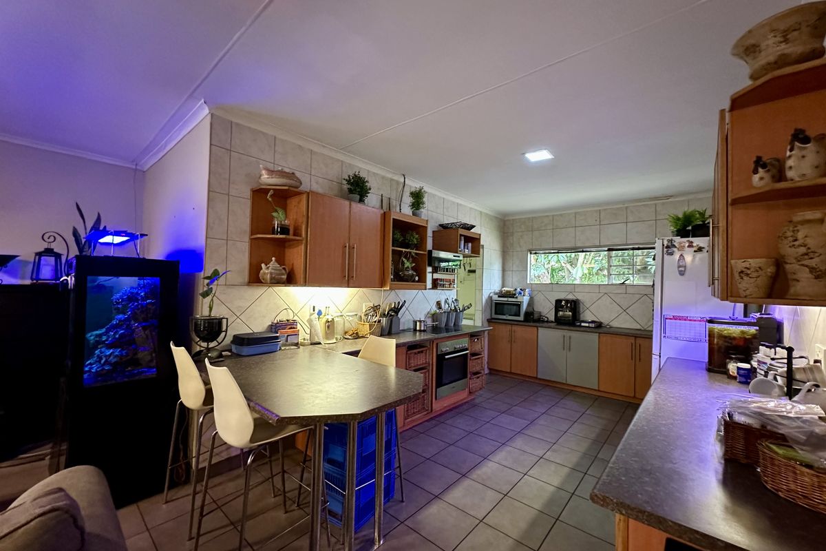 A functional kitchen featuring wood-toned cabinetry, tiled backsplash, built-in oven, and a breakfast bar area with tiled flooring throughout.