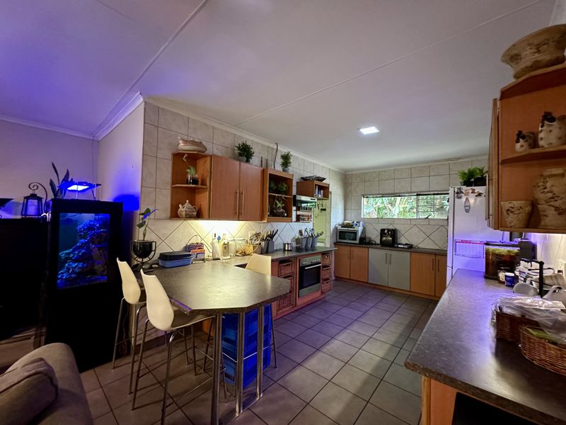 A functional kitchen featuring wood-toned cabinetry, tiled backsplash, built-in oven, and a breakfast bar area with tiled flooring throughout.