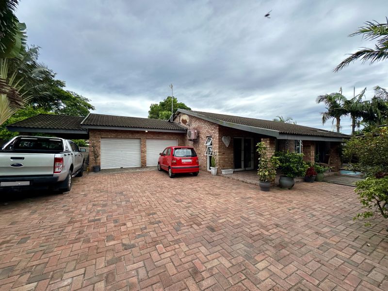 Front elevation of a single-story brick house featuring a double garage, paved driveway, and tiled roof.
