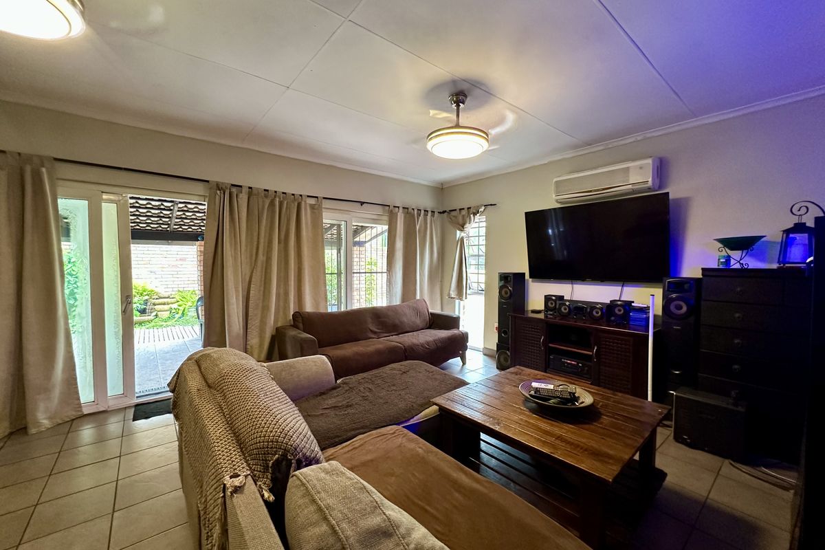 A comfortable living room featuring tiled floors, a split-system air conditioner, and sliding glass doors that provide direct access to the outdoor patio area.
