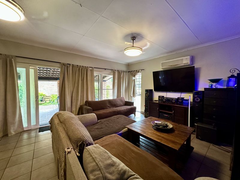 A comfortable living room featuring tiled floors, a split-system air conditioner, and sliding glass doors that provide direct access to the outdoor patio area.