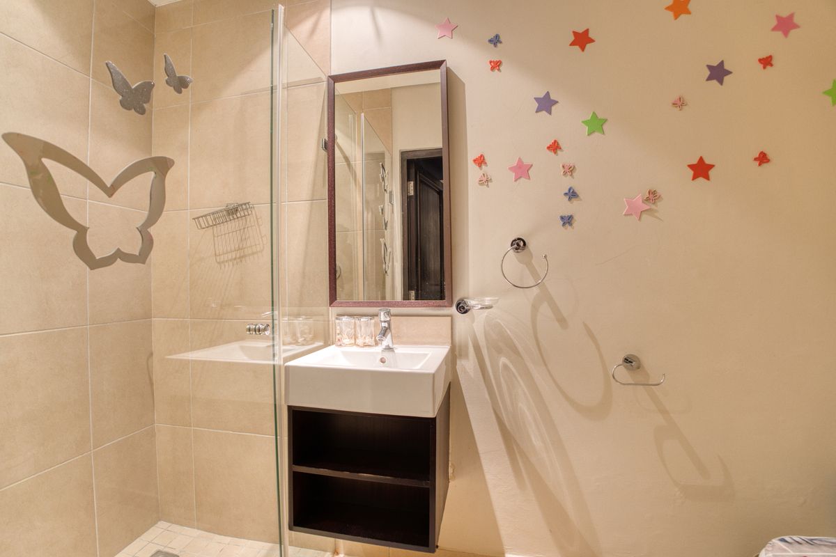 A compact bathroom featuring a wall-mounted vanity with a basin, a glass-enclosed shower, and a framed mirror.