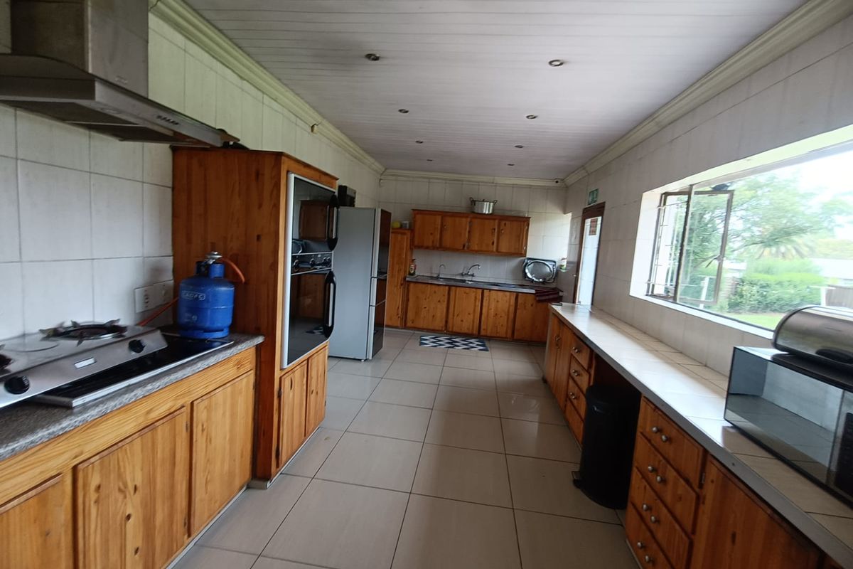 Spacious kitchen featuring extensive wooden cabinetry, built-in oven, extractor fan, and tiled flooring with ample counter space and natural light.