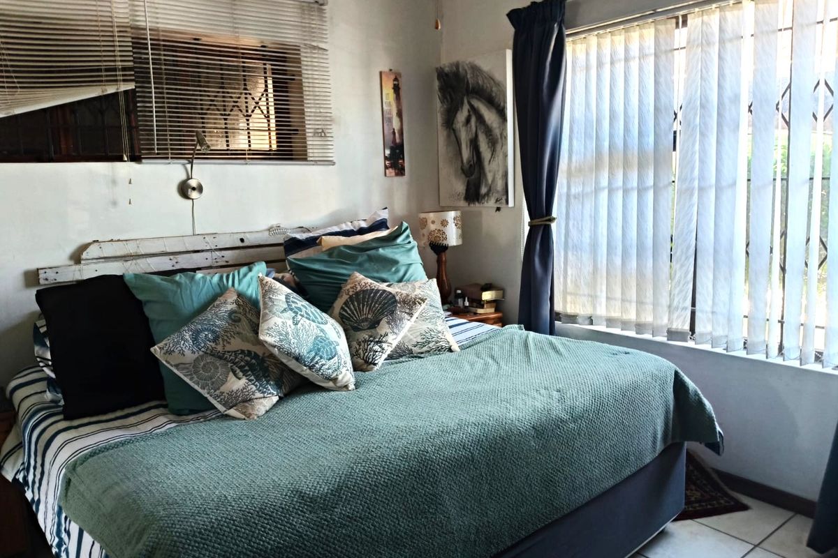 A bedroom featuring tiled flooring, vertical window blinds, and horizontal venetian blinds, providing natural light and a functional layout.