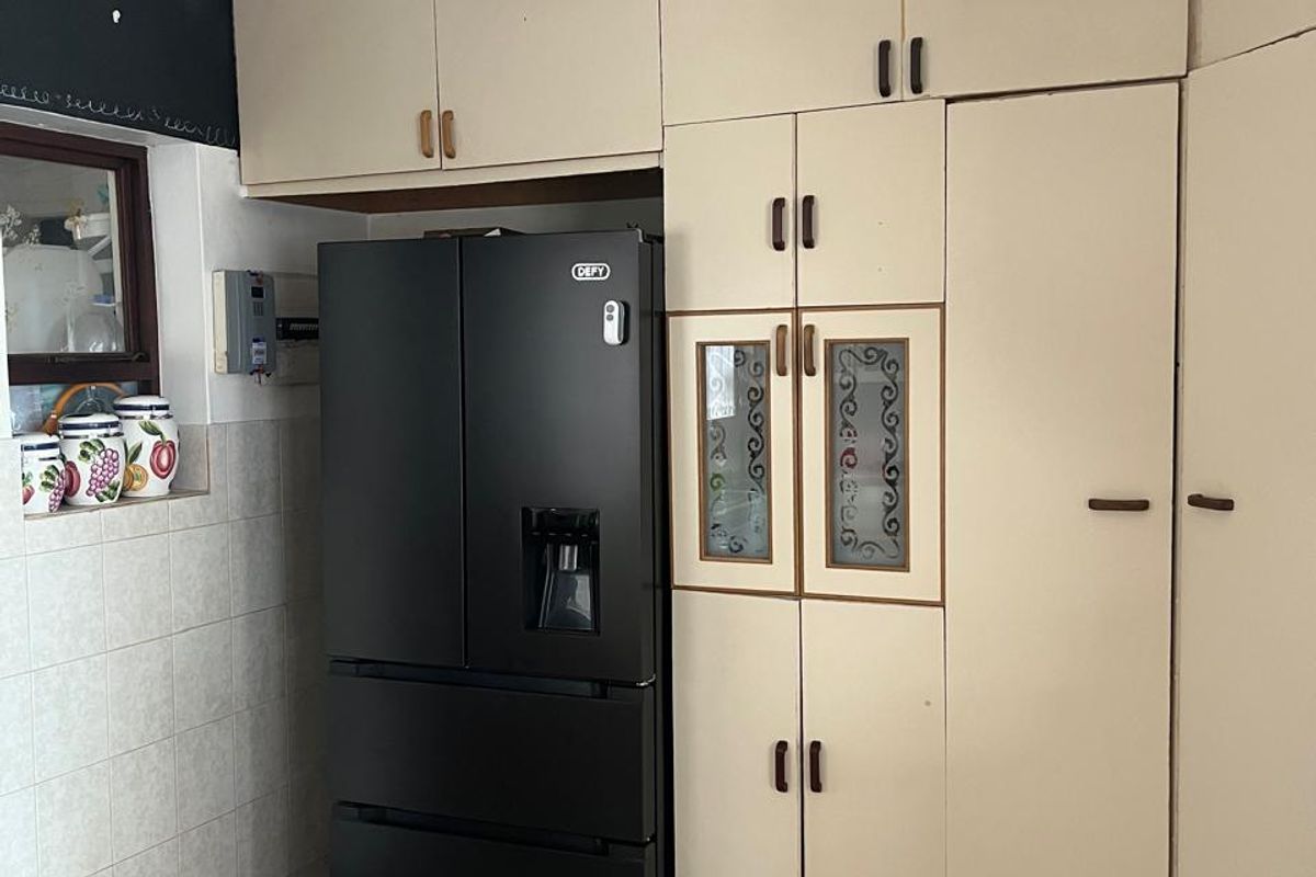 A kitchen area featuring built-in cream cabinetry with glass-panel inserts and tiled flooring, providing functional storage space.