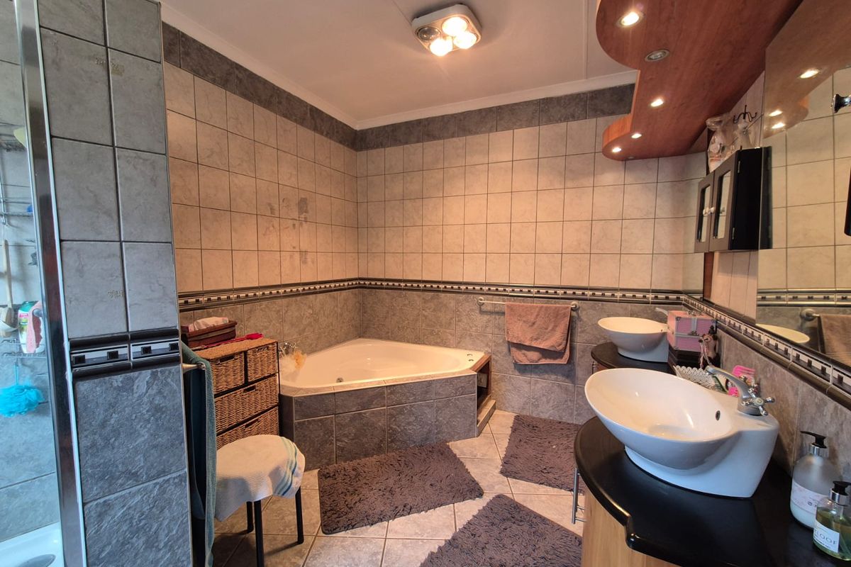 A spacious bathroom featuring a corner bathtub, dual vessel sinks on a vanity, and a separate shower enclosure with tiled finishes.