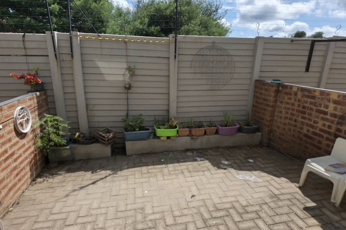 A private rear courtyard featuring brick walls, concrete panel fencing, and paved flooring, providing a functional outdoor space.