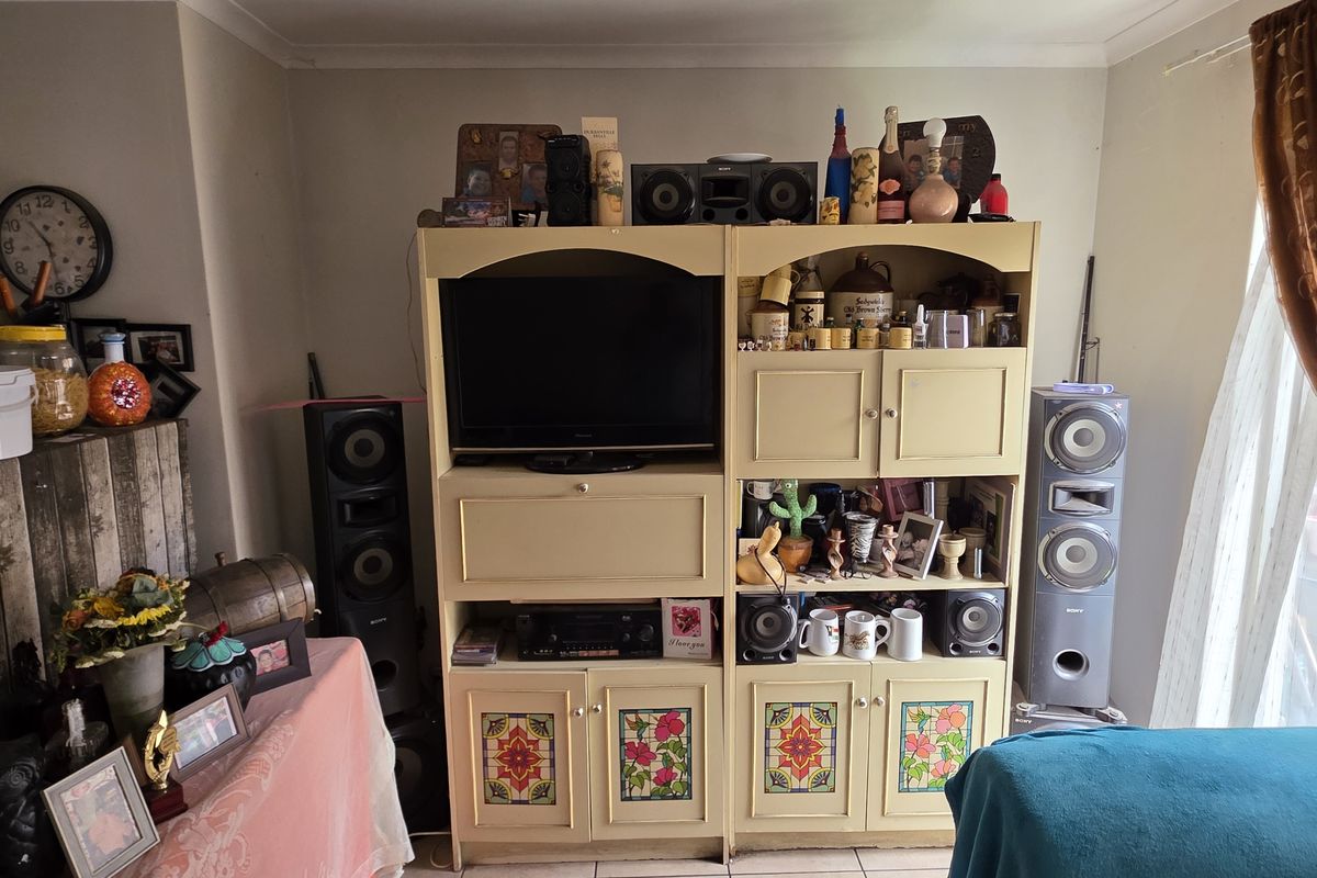 A living room area featuring tiled flooring and a built-in entertainment unit with decorative glass panel detailing.