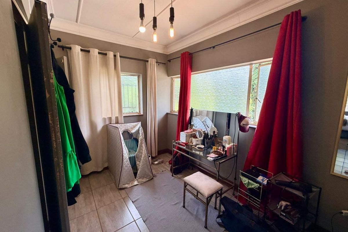 A bedroom featuring tiled flooring, large windows with curtain rods, and decorative ceiling molding.