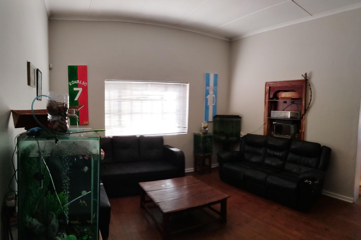 A living room featuring timber flooring, a built-in wooden wall niche, and a window with fitted blinds.