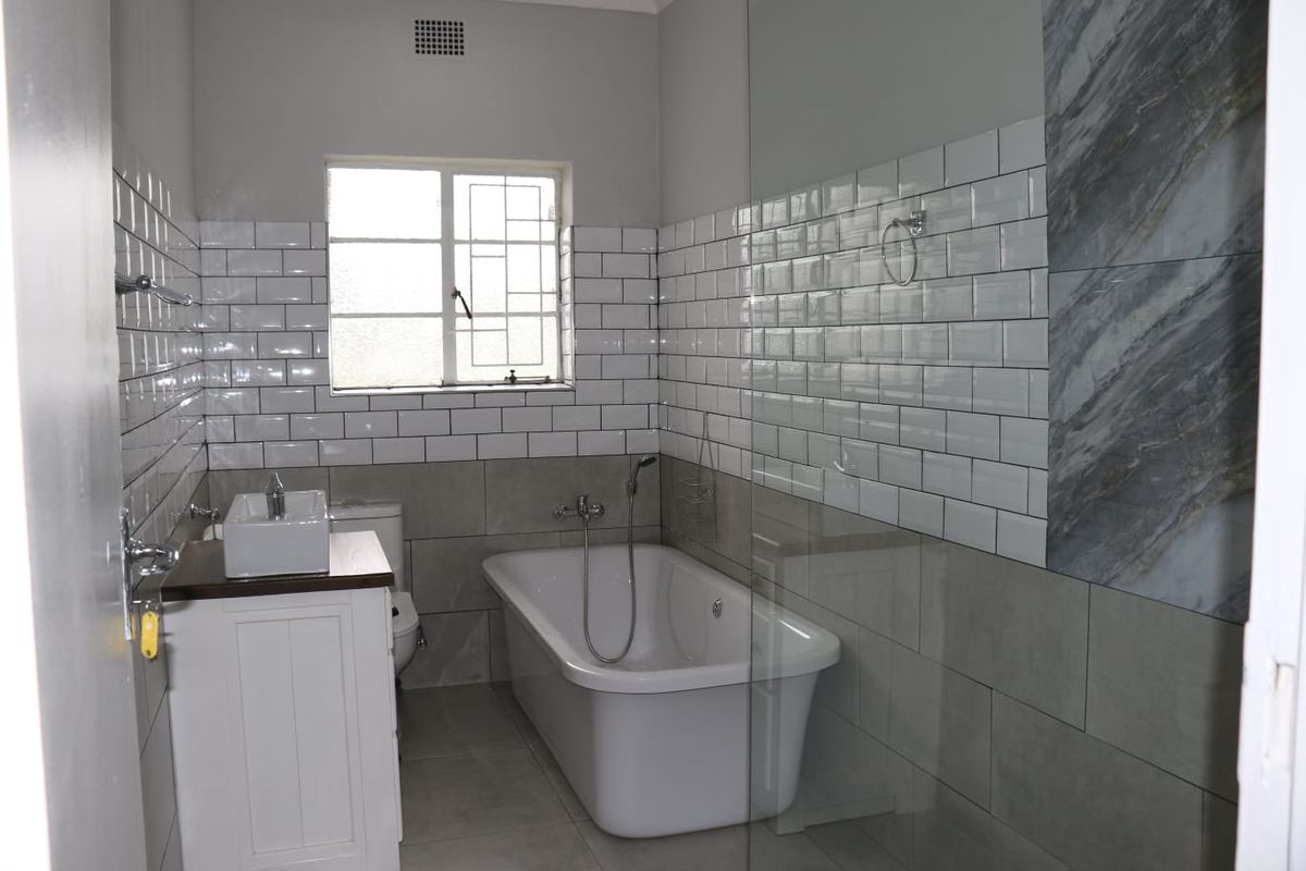 A modern bathroom featuring a freestanding bathtub, a glass-enclosed shower area, a vanity with a vessel sink, and subway tile wall finishes.