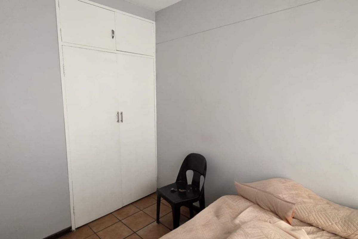 A bedroom featuring built-in cupboards and tiled flooring, offering a functional space ready for personalization.