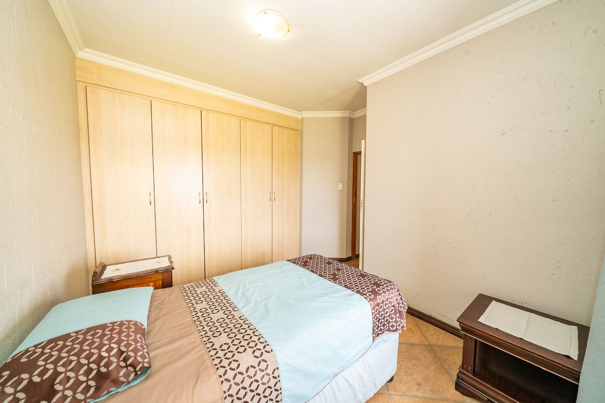 A bedroom featuring built-in wooden cupboards, tiled flooring, and crown molding.