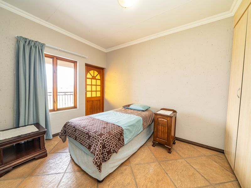 A bedroom featuring tiled flooring, built-in wooden cabinetry, and a wooden door leading to an outdoor balcony area.