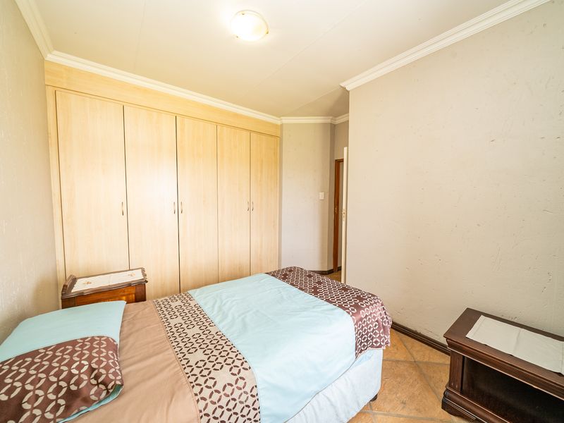A bedroom featuring built-in wooden cupboards, tiled flooring, and crown molding.