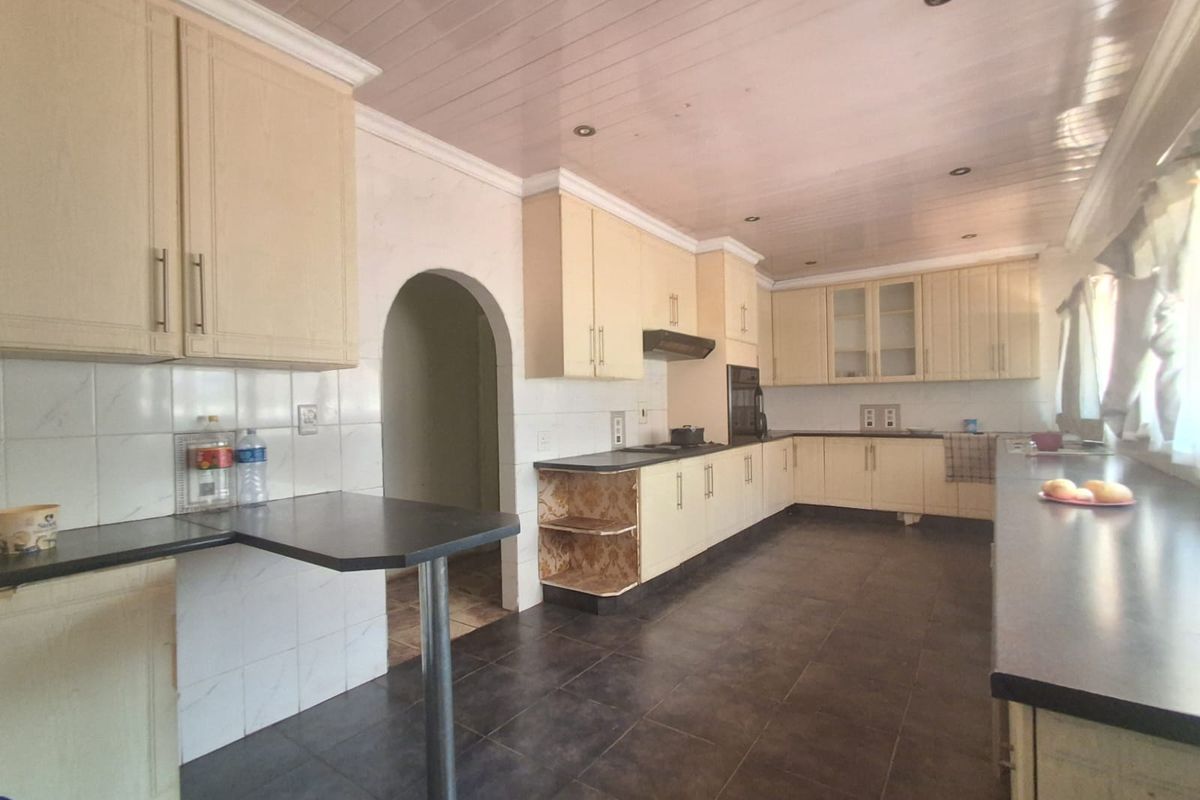 Spacious kitchen featuring extensive cabinetry, dark tiled flooring, built-in oven, and a breakfast bar area with an arched doorway leading to adjacent rooms.