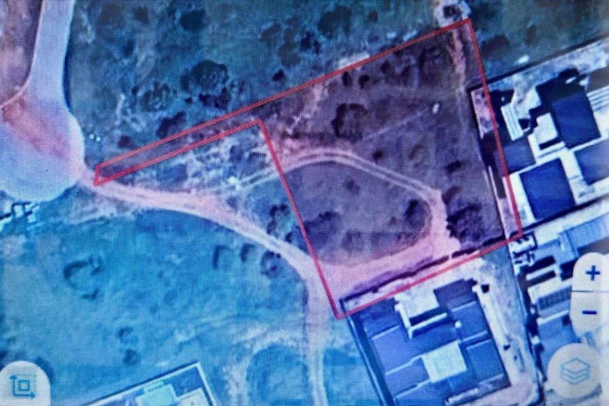 An aerial view of a vacant residential plot, showing the boundary lines and surrounding neighborhood layout.