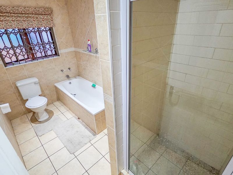 A functional bathroom featuring a bathtub, separate shower enclosure, and tiled finishes, offering a practical layout for a townhouse.