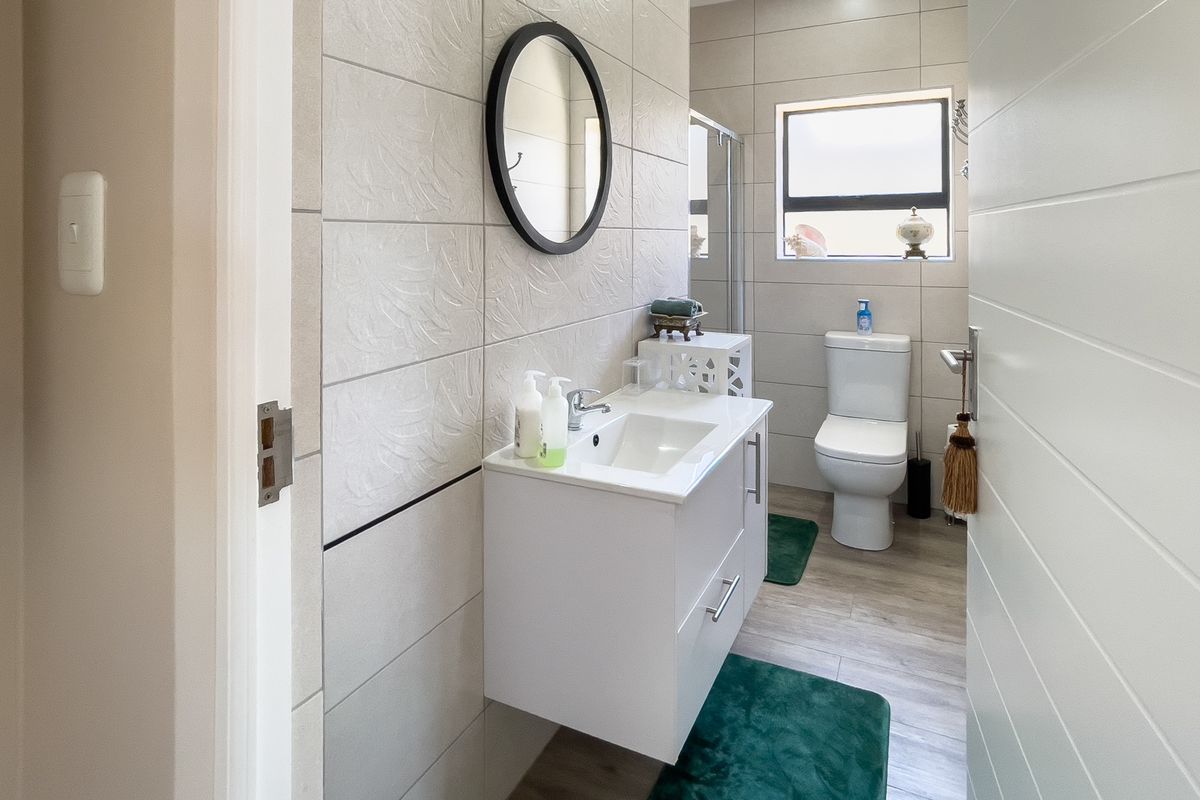 A modern bathroom featuring a wall-mounted vanity with a basin, a toilet, and tiled walls with a neutral finish.