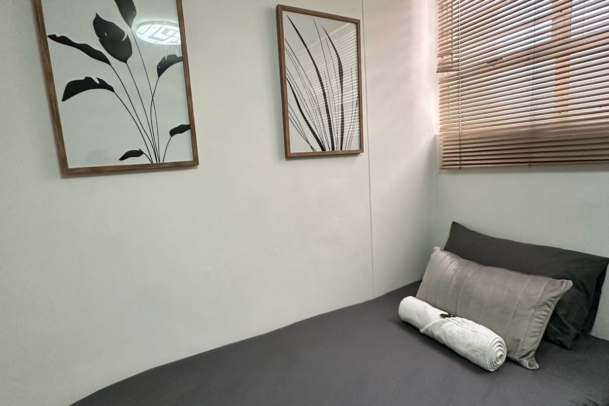 A compact bedroom featuring a window with fitted wooden blinds, providing natural light and a neutral backdrop.