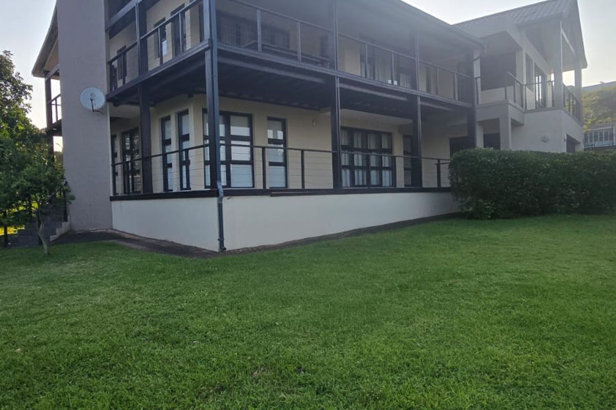 A view of the rear elevation of the house, featuring a multi-level balcony structure with black metal framing and glass balustrades overlooking a lawn.