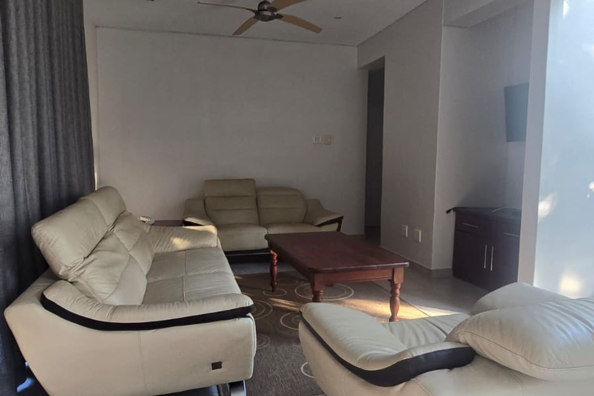 A spacious living room featuring large format floor tiles, recessed ceiling lighting, and dual ceiling fans, offering a comfortable and functional living space.