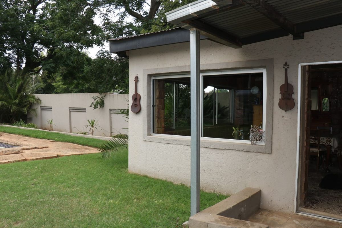 Exterior view of the rear patio area featuring a covered walkway, sliding window, and access to the garden and pool area.