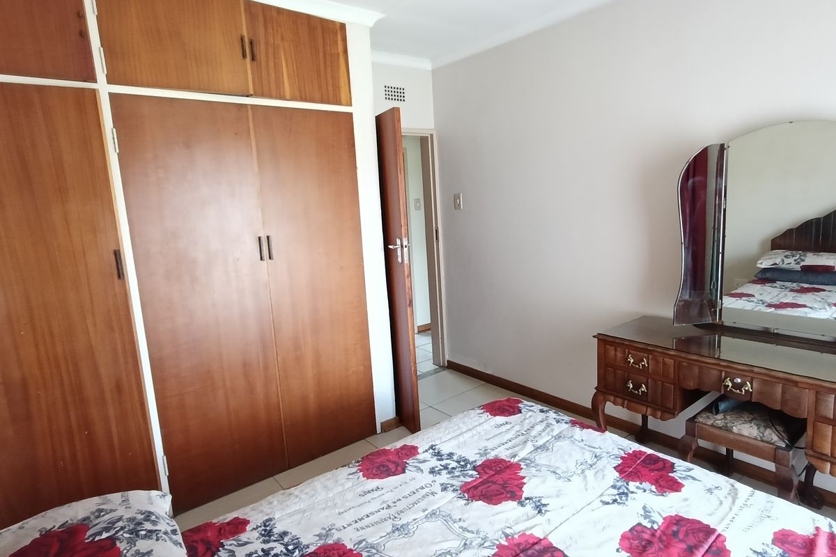 A bedroom featuring built-in wooden cupboards with overhead storage and tiled flooring, providing functional storage space.
